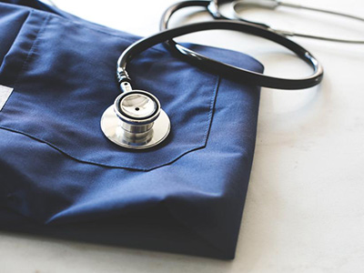 A stethoscope resting on top of a nurse's scrubs